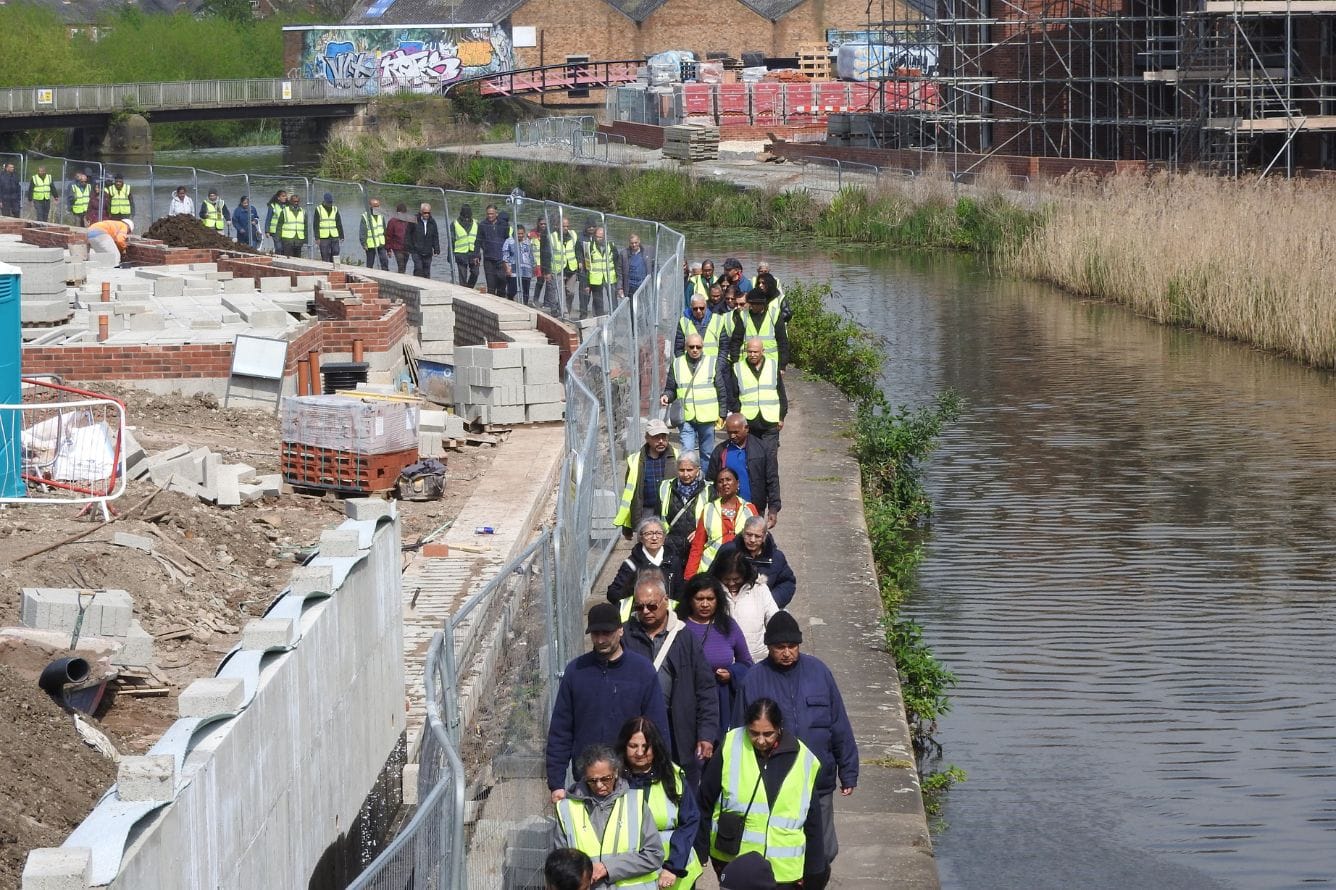 A large group of people walk along the canal.